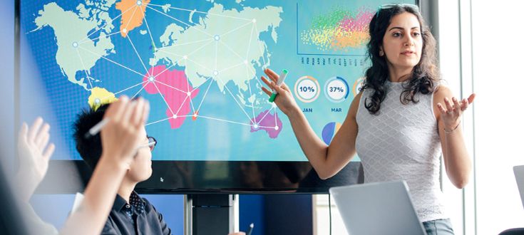 A supply chain management professional giving a presentation in front of a world map