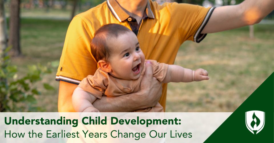 A parent in a yellow shirt plays with his infant in the park
