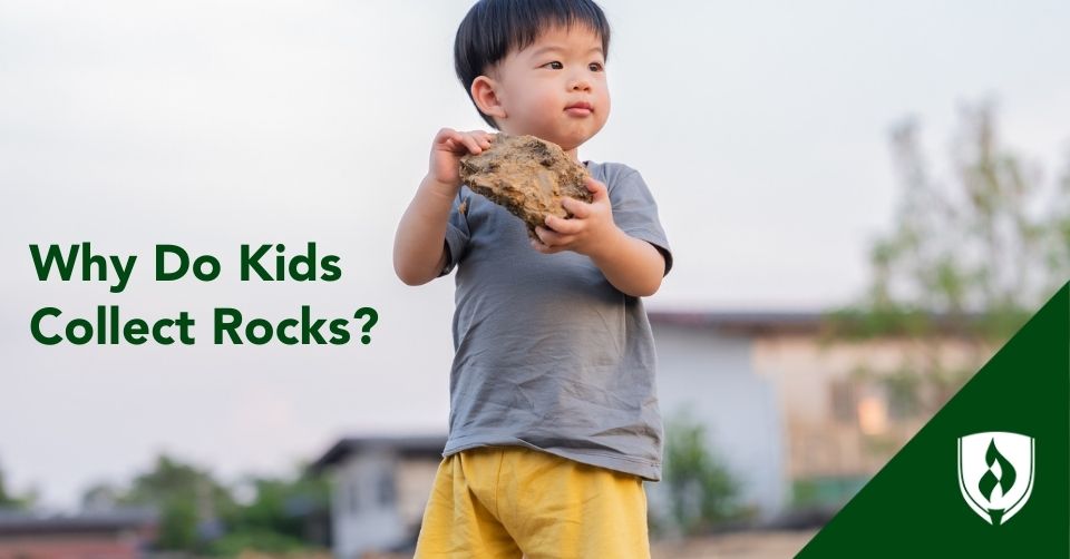 An adorable toddler holds a big rock with both hands