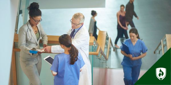 Medical assistants, nurses and doctors walk past each other