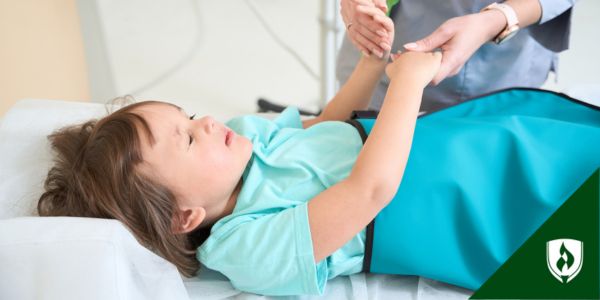 A rad tech holds a child's hands on the bed of a diagnostic scanning machine