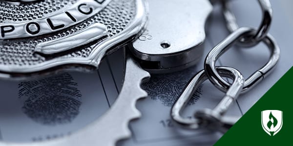 Photograph of a badge resting on top of a pair of handcuffs.