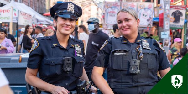 Two peace officers stand side by side in a city