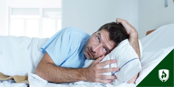 A traumatized-looking man clutches a pillow on his hospital bed