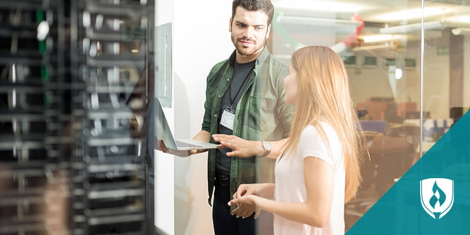 man and woman talking in front of computer servers