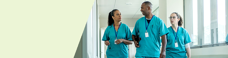 Three Health Sciences Associates professionals in teal scrubs walking down a hallway